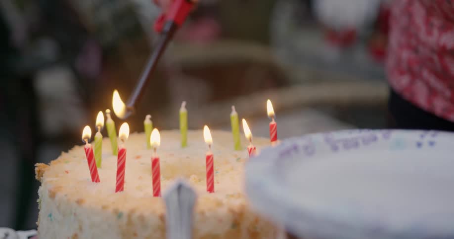 Someone is lighting the candles on a birthday cake