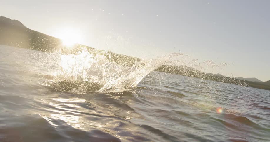 A girl runs on a dock and jumps into a lake at sunset