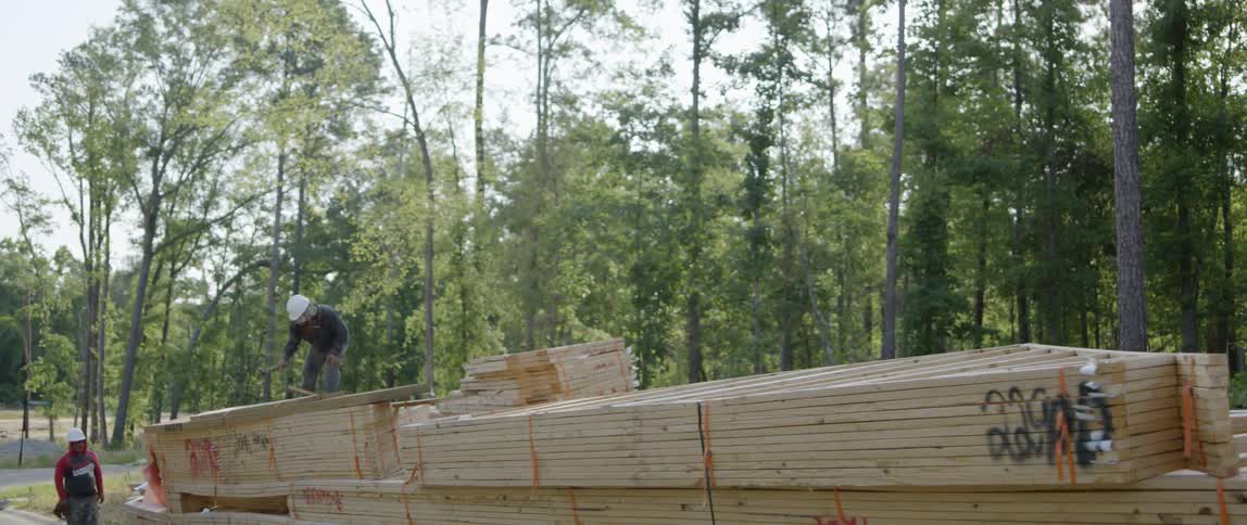 A worker at a construction site is unstrapping a load of wood