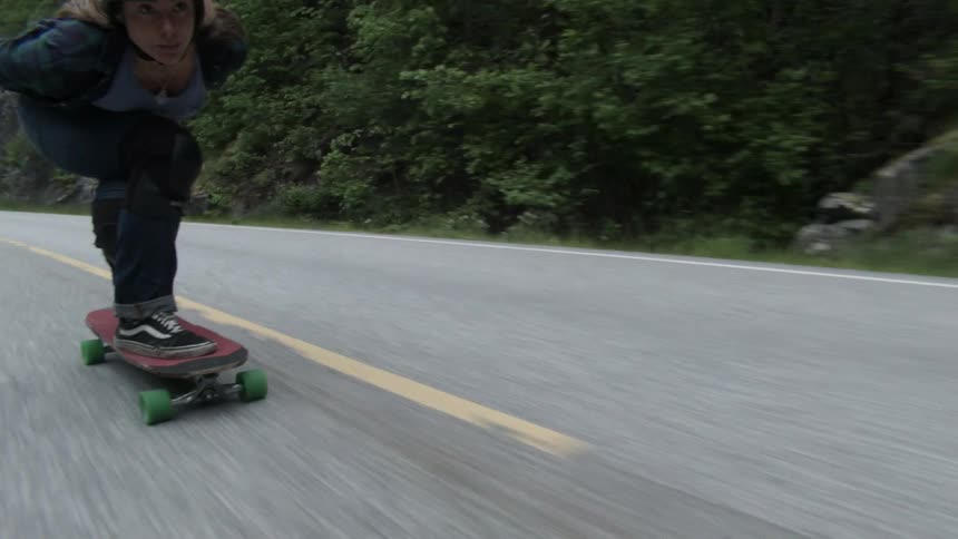Person rides a skateboard down a country road