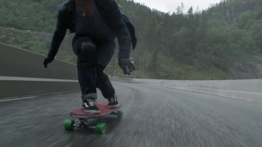 A woman rides a skateboard down a street