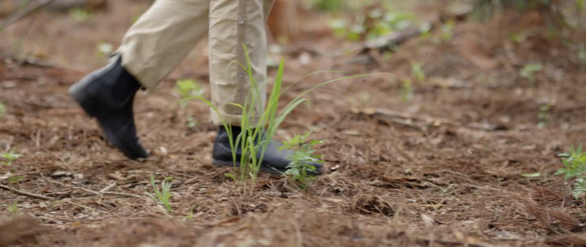 Someone in black boots walking through the dirt