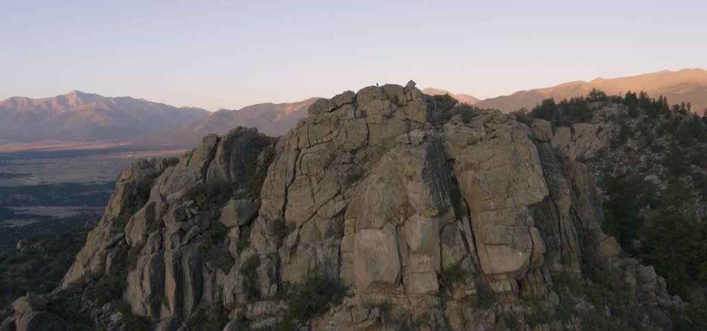Trees cling to rocks on a cliff face in the desert at dawn