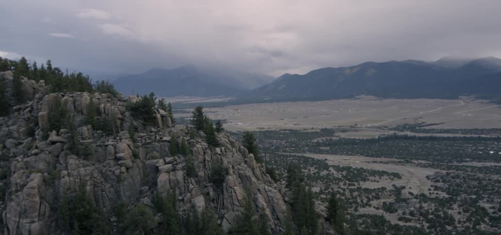 Storm clouds hang over a desert valley and hills