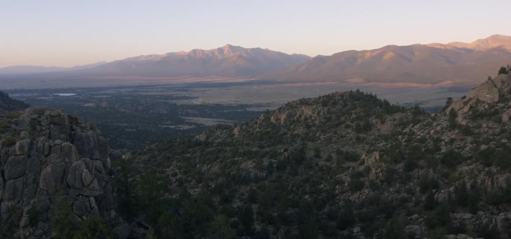 Dusk is settling over a desert valley and mountains