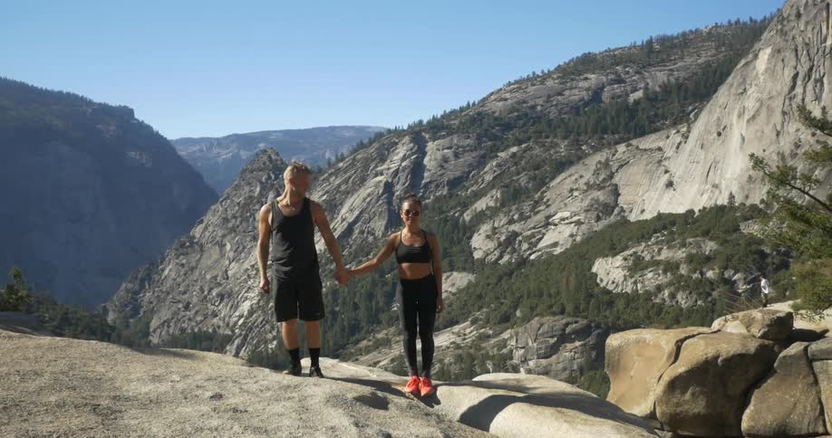 A man and woman holding hands on a rocky hill
