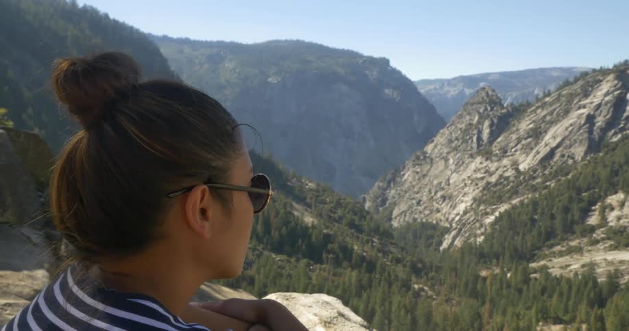 Woman views some mountains from a cliff