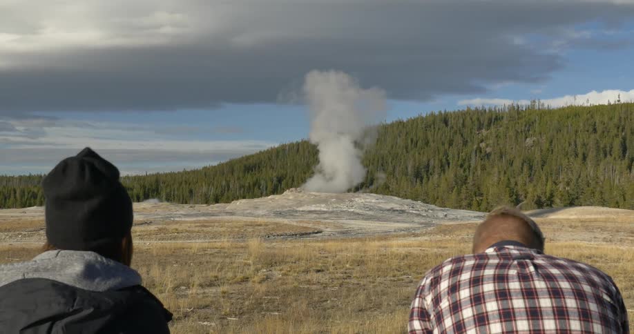 Two people watch as smoke comes out of the ground ahead
