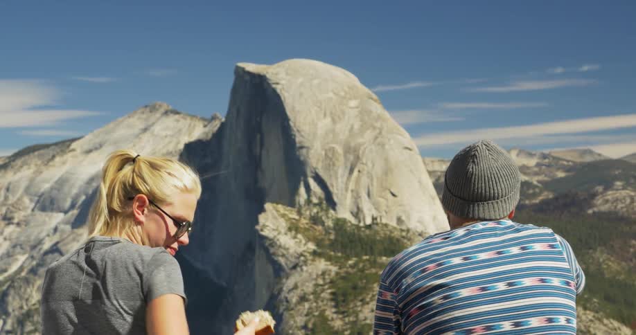 Man and woman sit on top of a mountain