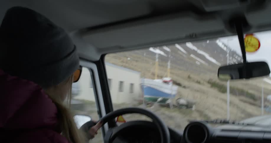 A woman drives a truck through a mountain village