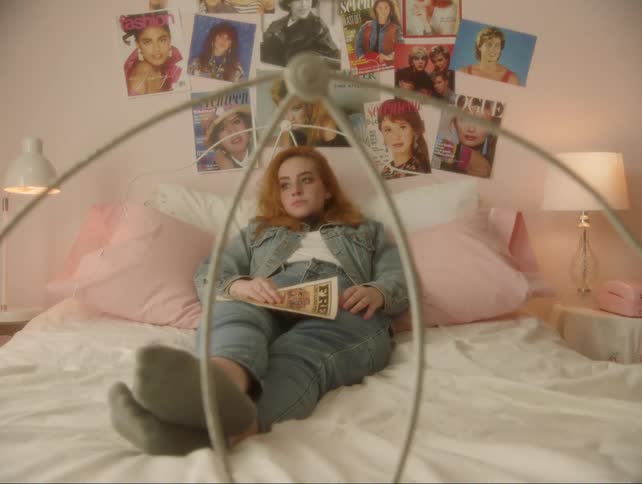 A woman lays on the bed reading a comic book before putting it down