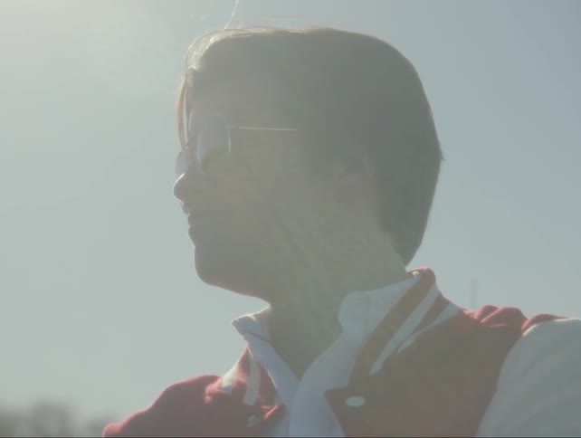 High school boy leans against car