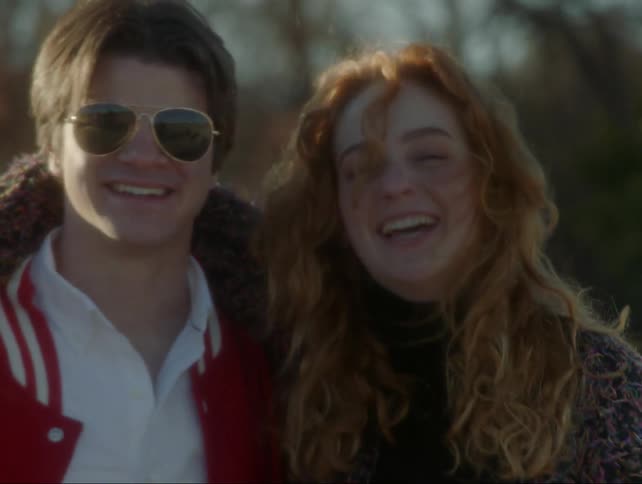 A man and woman smile and laugh outside