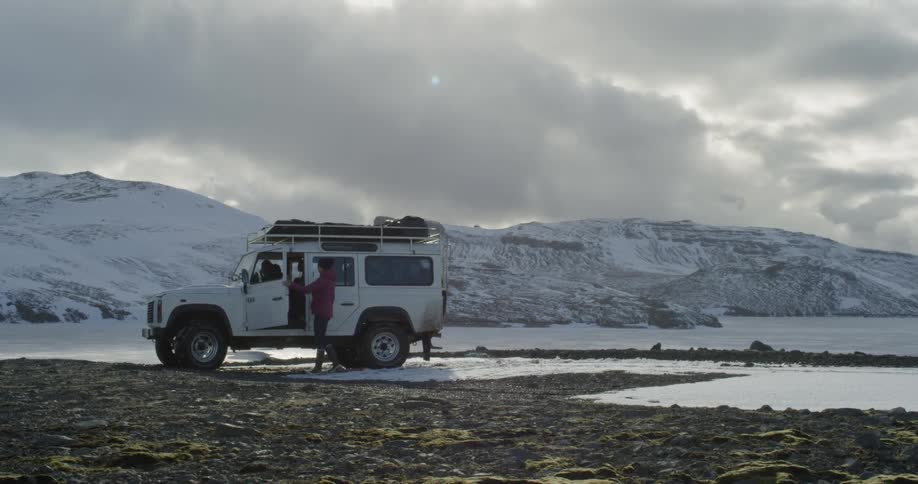 A driver exits a Land Rover they parked on top of a snowy hill