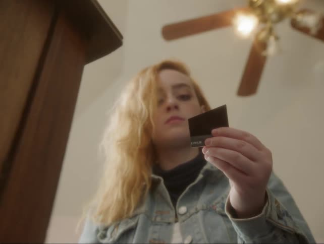 A teenage girl is slicing a polaroid in half with a pair of scissors