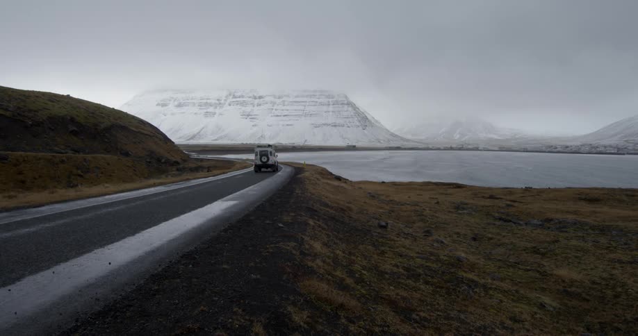 A Land Rover drives along a wet winter highway