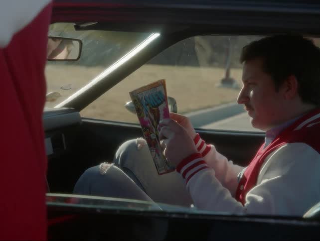 A man reads an x-men comic book in a sports car