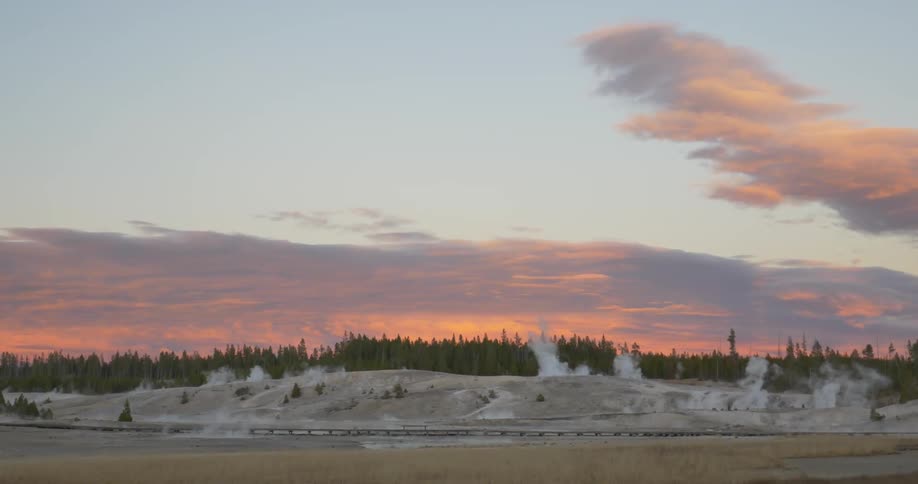 Large field with steam rising from the surface in spots at sunset