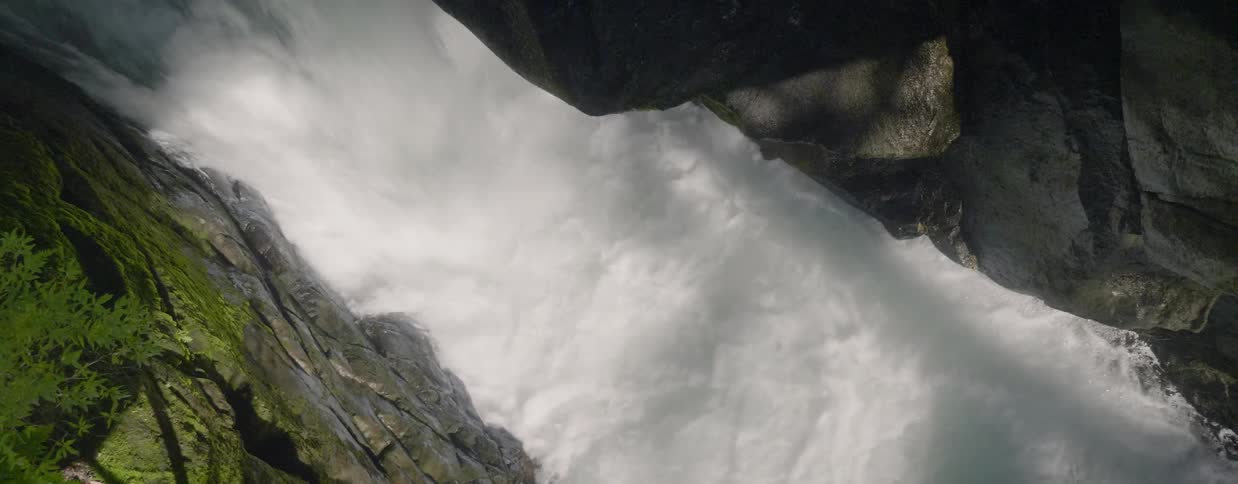 Water is pooling and flowing between boulders in a stream during the day