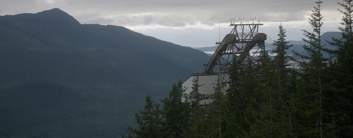 A gondola terminal high up in mountainous region on cloudy day