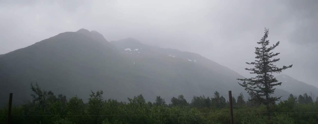Clouds and mist hover over a mountain