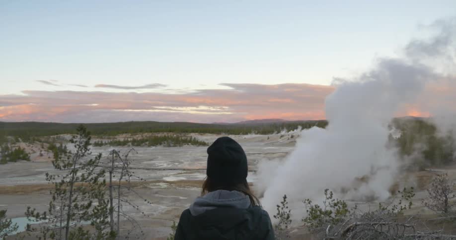 Person looking out at a smoking geyser