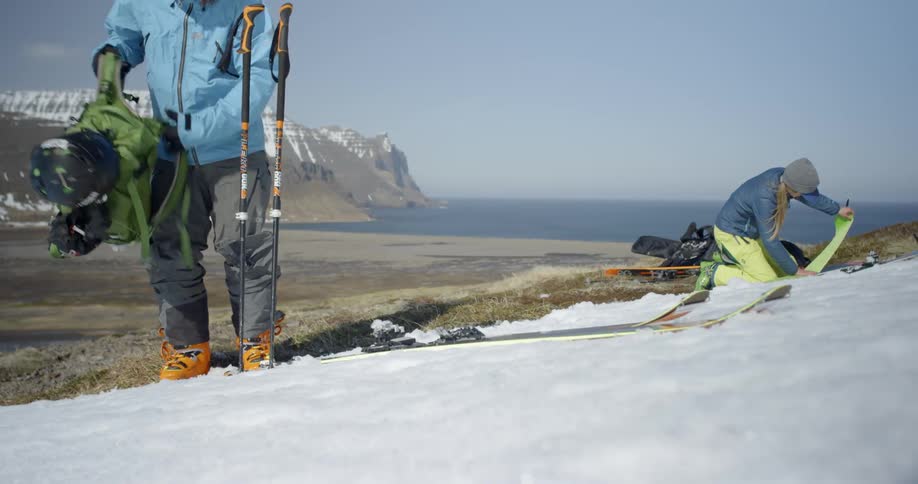 Skiers transitioning from hiking to skinning in a snowy wilderness area