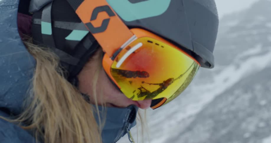 A woman in a helmet prepares to ski down slope reflection in goggles