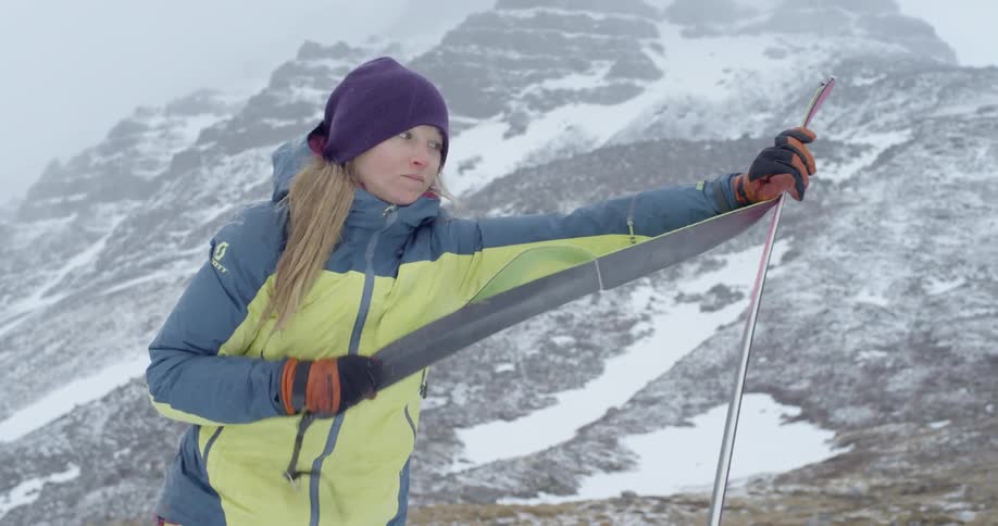 Woman preparing equipment in a snowy mountainous area