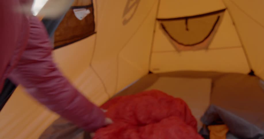 Woman arranging sleeping bag in tent