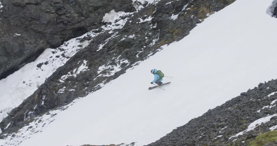 A skier jumps between mossy rocks on a mountainside
