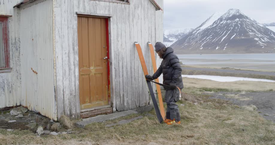 A man puts backcountry skins on skis before walking up the mountain