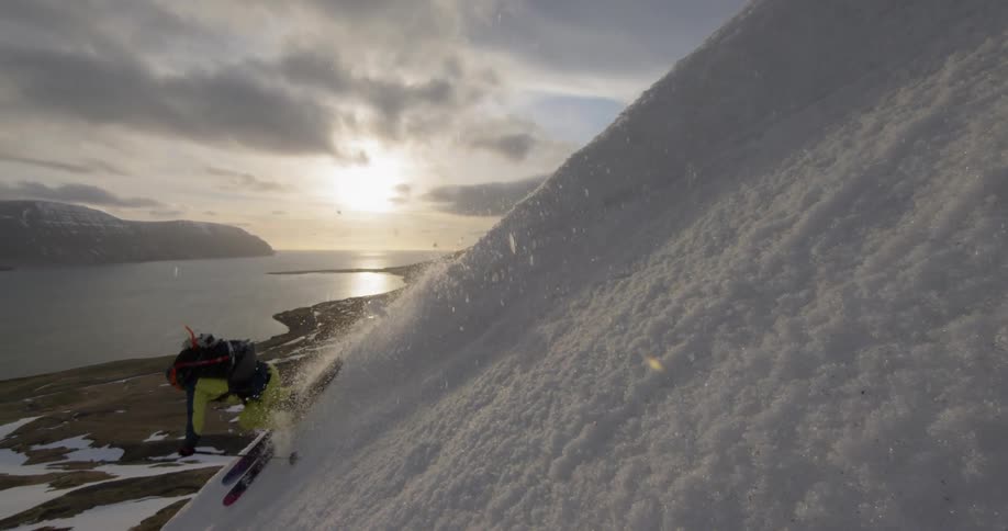 A skier turns on ridge facing into the sun at sunset