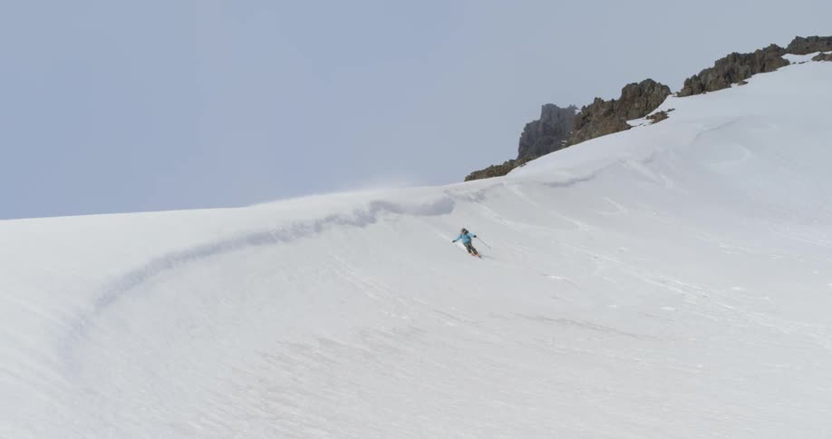 A professional athlete skis down a snowy ridge