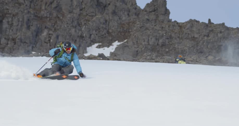 A man skiing down a steep mountain slope covered in snow towards camera