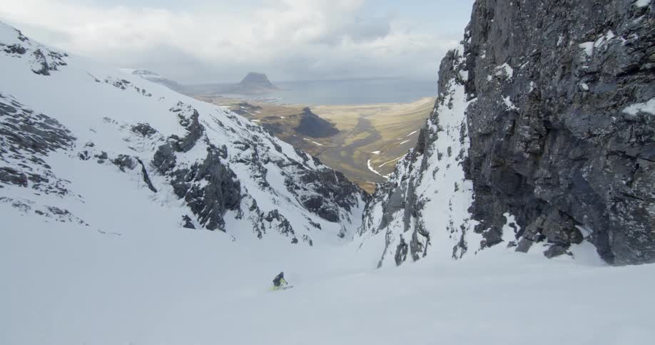 Person skiing down a snow covered couloir during a storm