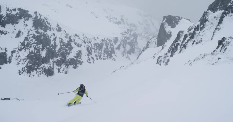 Female skiing down a steep slope as it's snowing