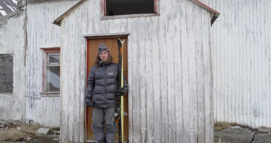 Man holds skis next to an old building