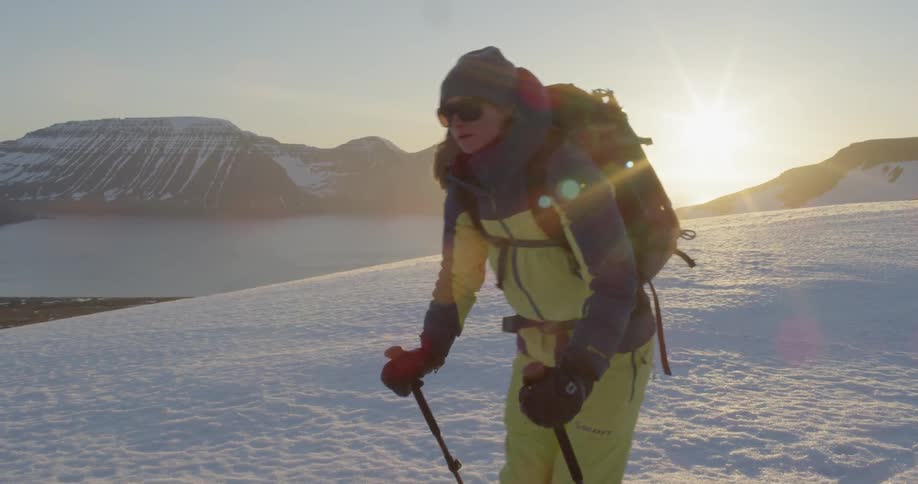 A woman cross country skis at sunset