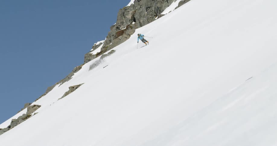 A skier turns down a rocky snowy mountainside