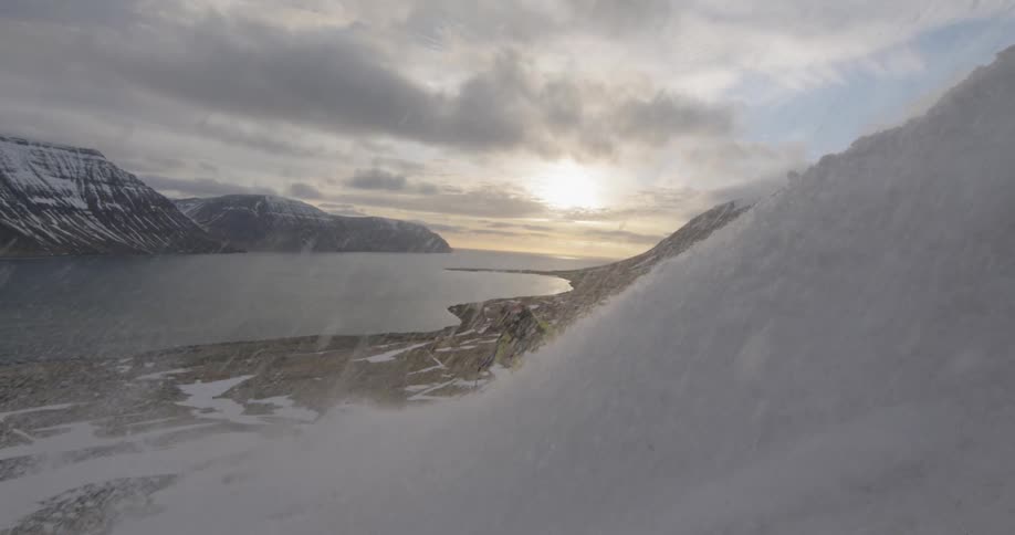 A skier throws snow in front of camera at sunset