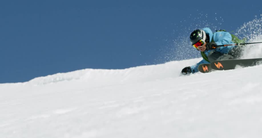 An extreme skier carves down a snowy mountainside in the spring