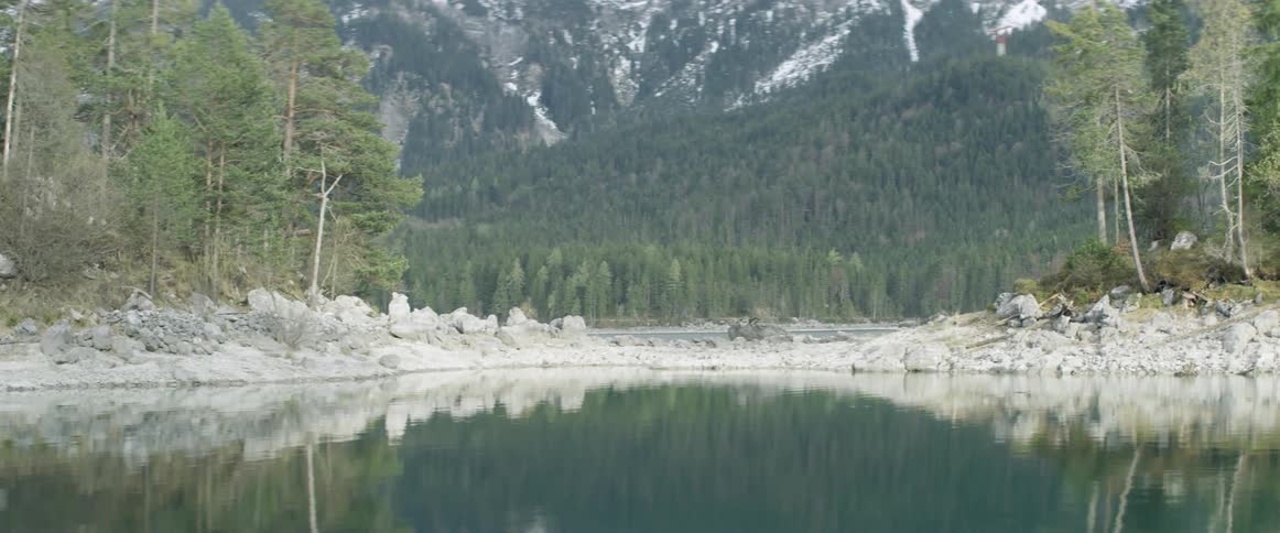 A mountain scene is reflected in a lake during the day