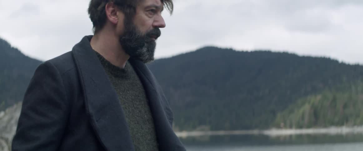 A man walks next to a mountain lake