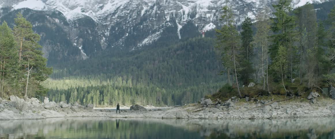 A man is walking along the edge of a lake