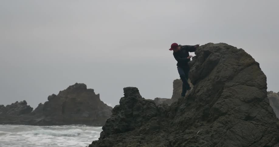 Man stands on some rocks by the water
