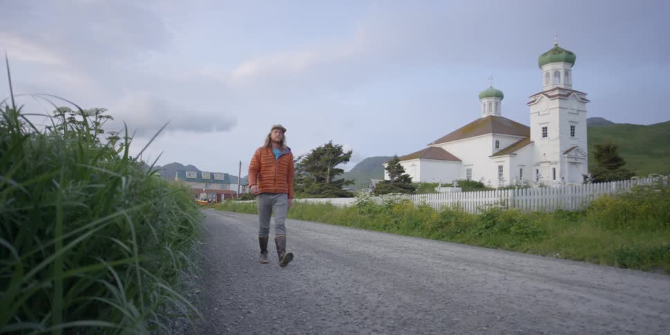 A man is walking down the road next to a church