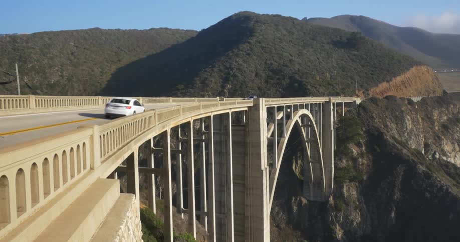 Large bridge with cars driving near a mountain range