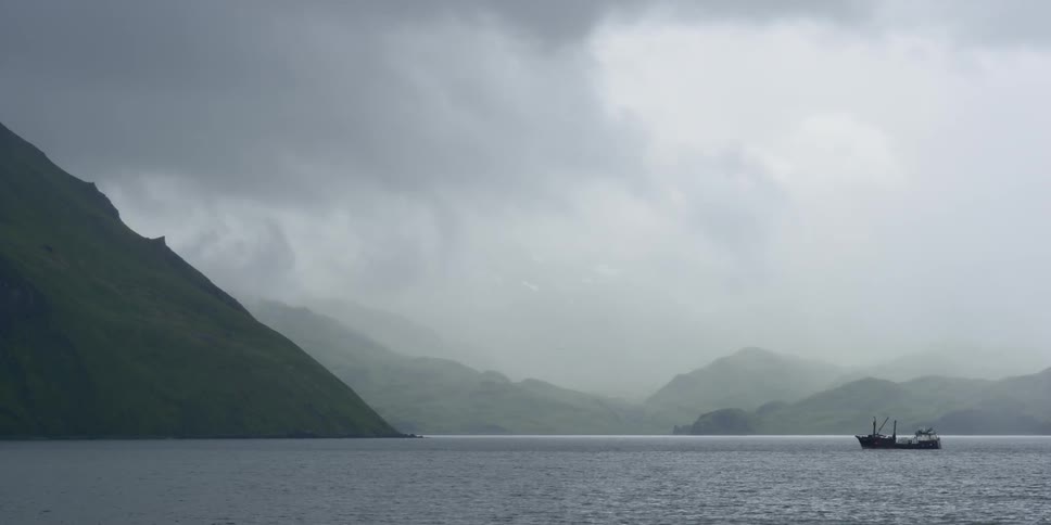 A large ship is sailing across a lake on a foggy day