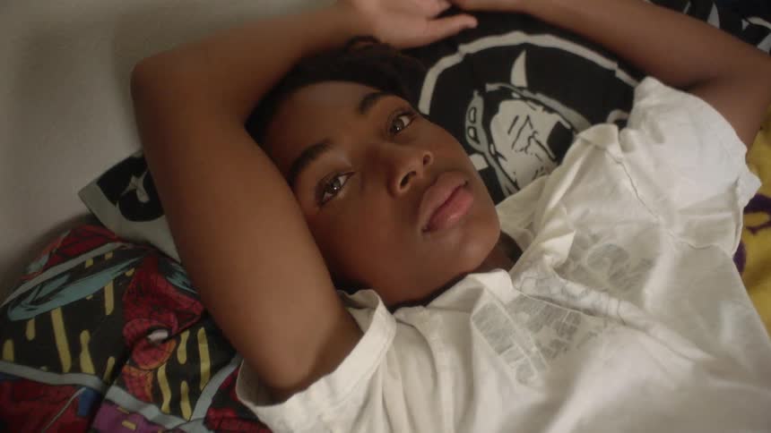 A kid is lying in the bed looking at the ceiling